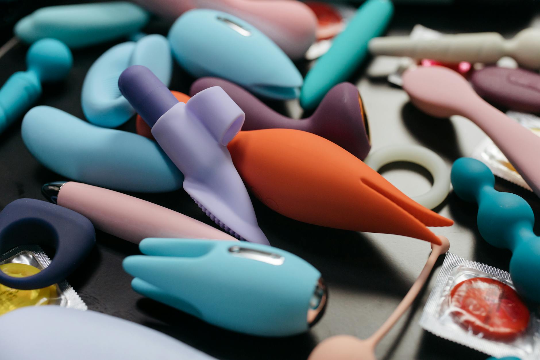 Woman holding two colorful vibrators, considering her options for sexual wellness.