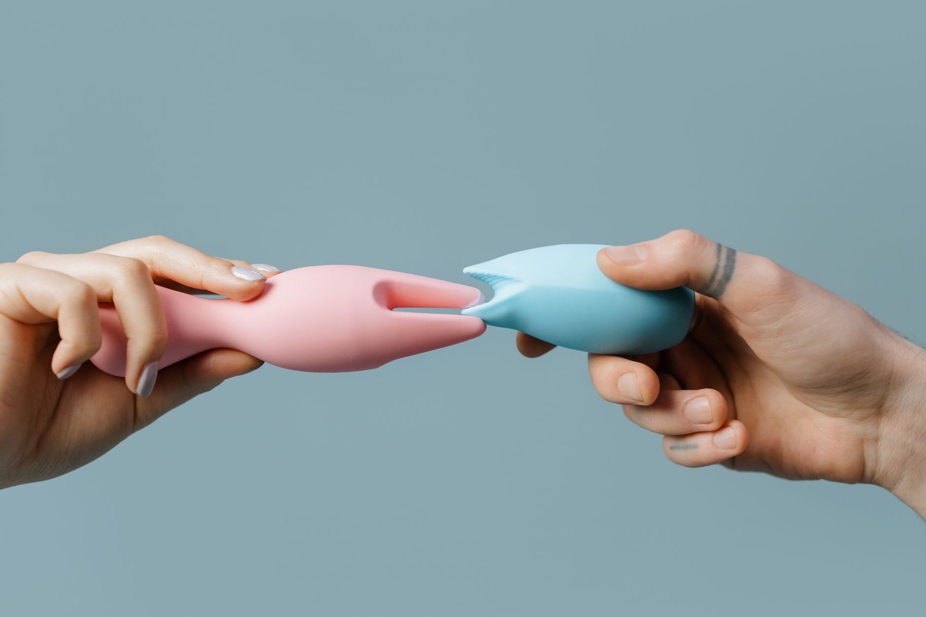 Hands holding pastel-colored silicone toys against a white background.