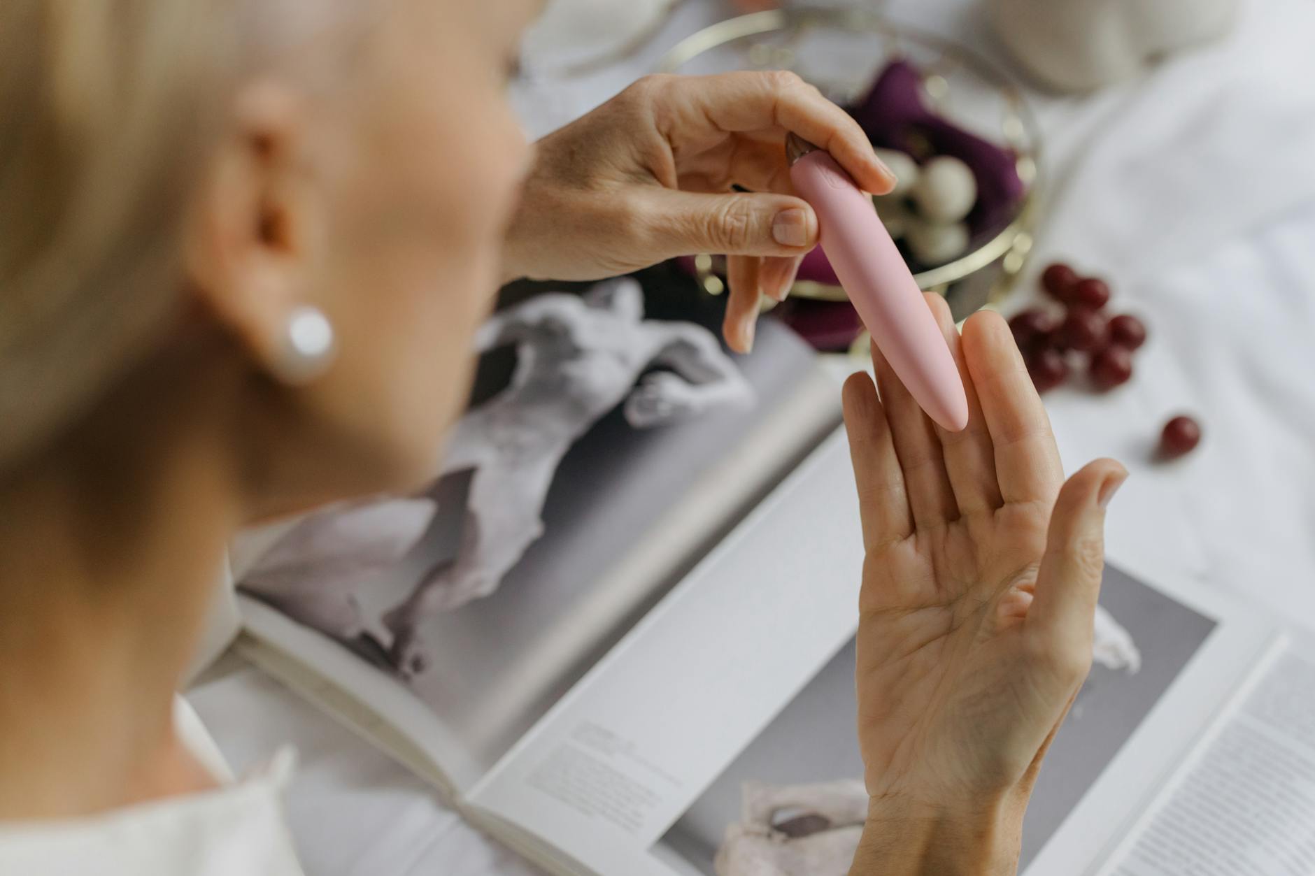 Woman holding blue and pink silicone vibrators with a thoughtful expression