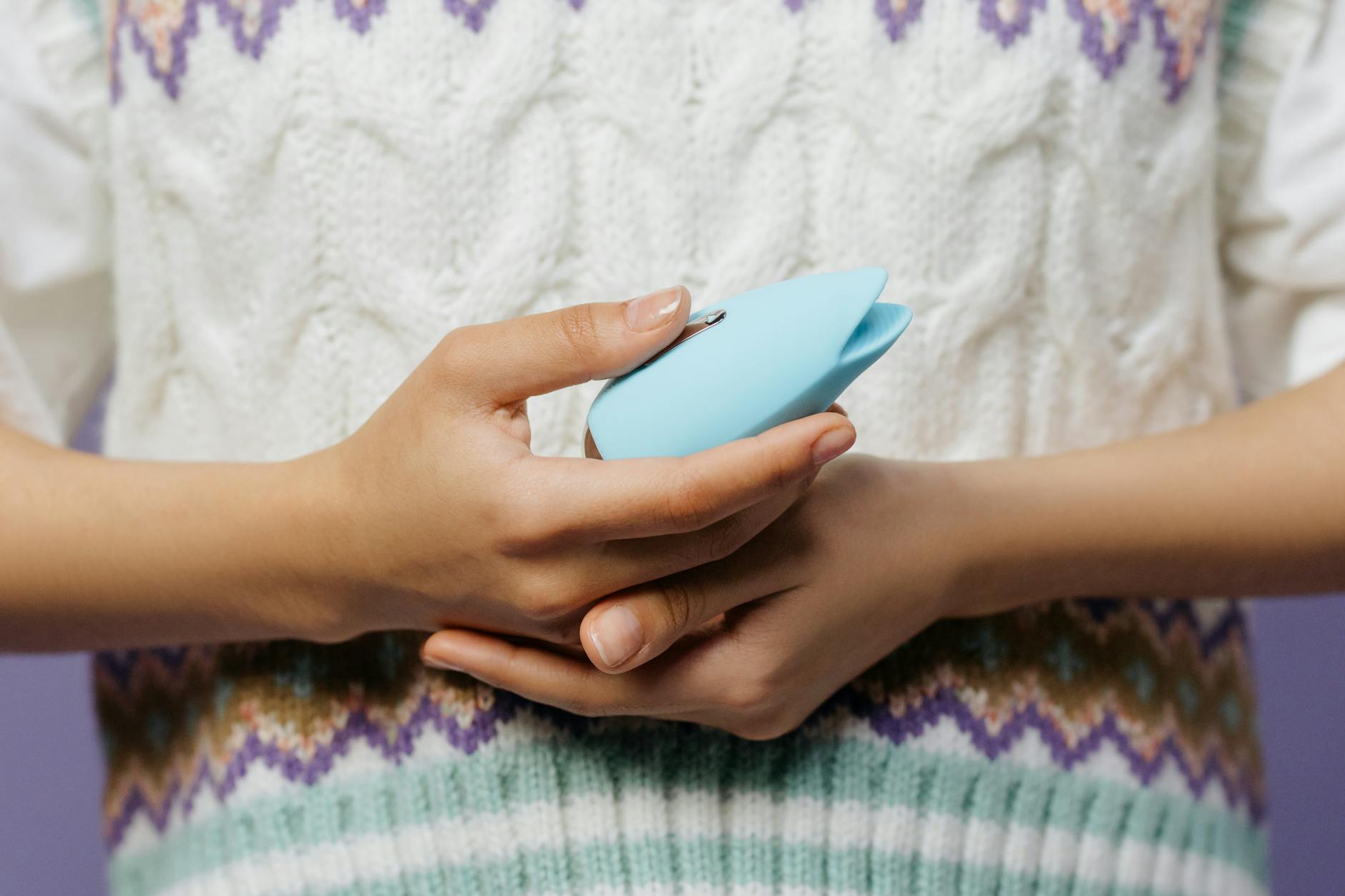 Hands holding a sleek vibrator against a textured background, representing comfort and personal choice