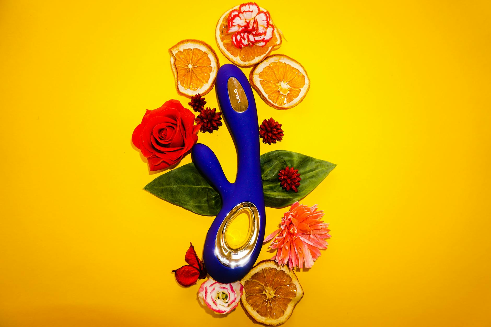 Lemon vibrator surrounded by fresh citrus fruit and flowers on a yellow background