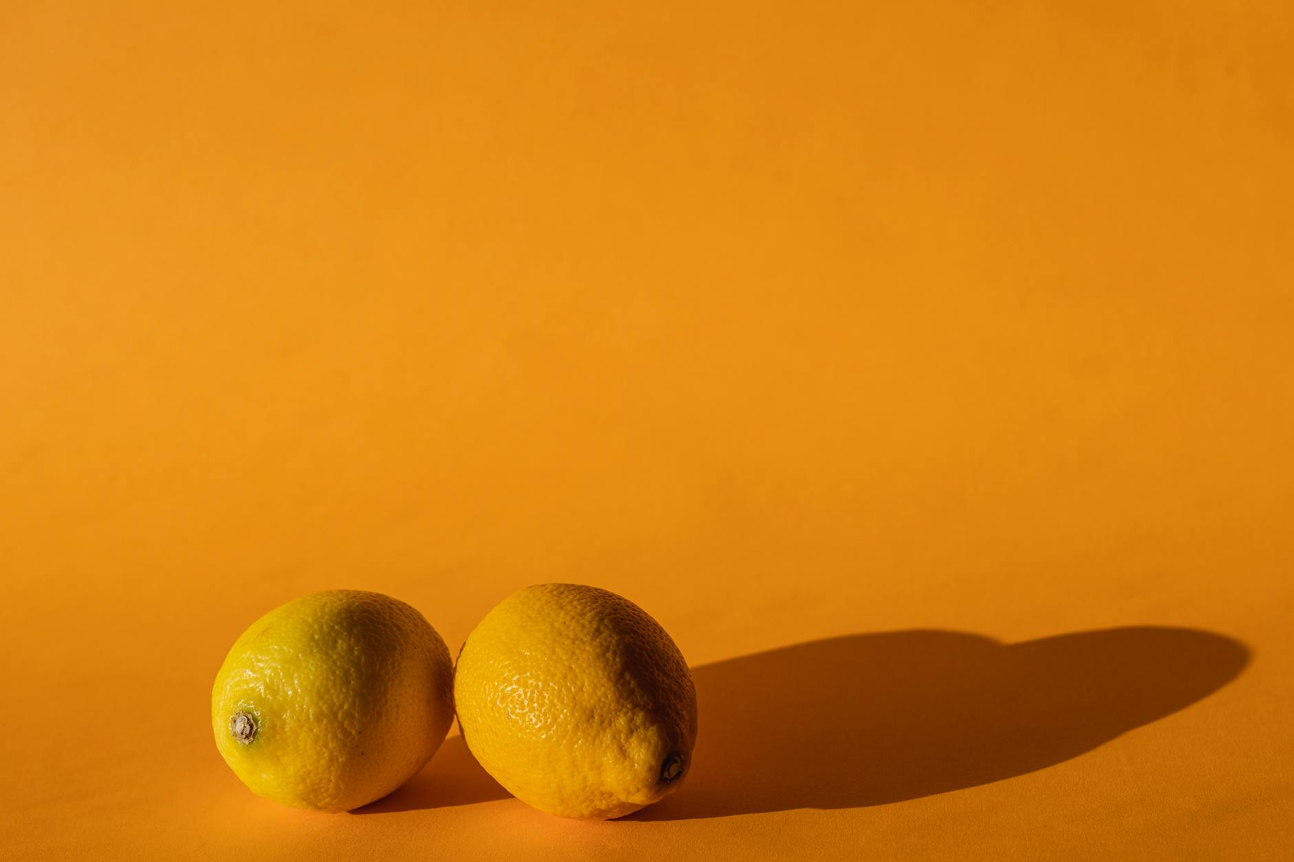 Ripe lemons arranged on a bright yellow background in natural daylight